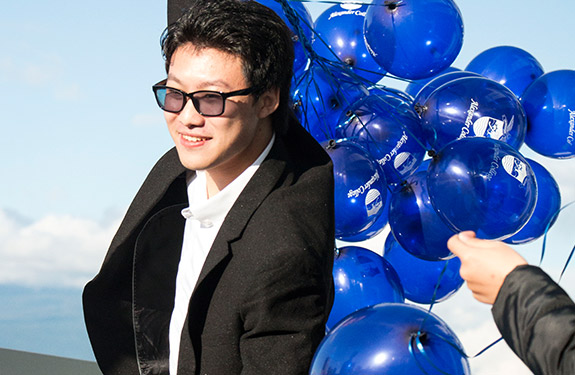 international student at Alexander College carrying balloons to graduation ceremony