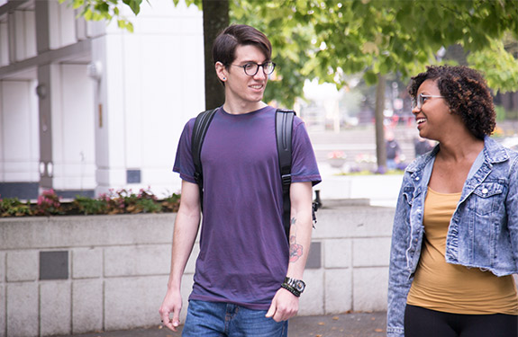 Two international students in Vancouver discussing English requirements at Alexander College while enjoying a walk