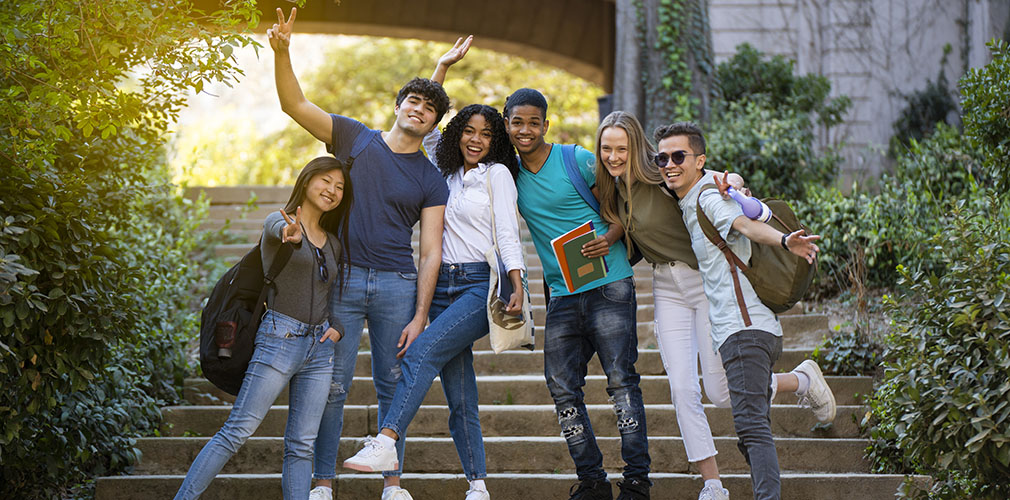 Group of young university multiracial students waving at the camera on some stairs