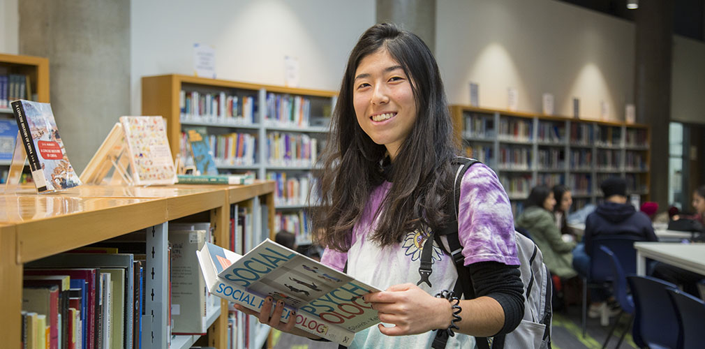 student holding a book in the library