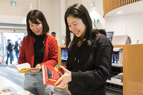 two students browsing books in the library