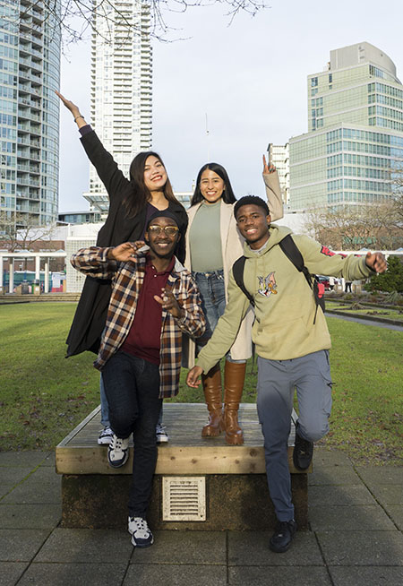 four students striking a pose outside Burnaby library