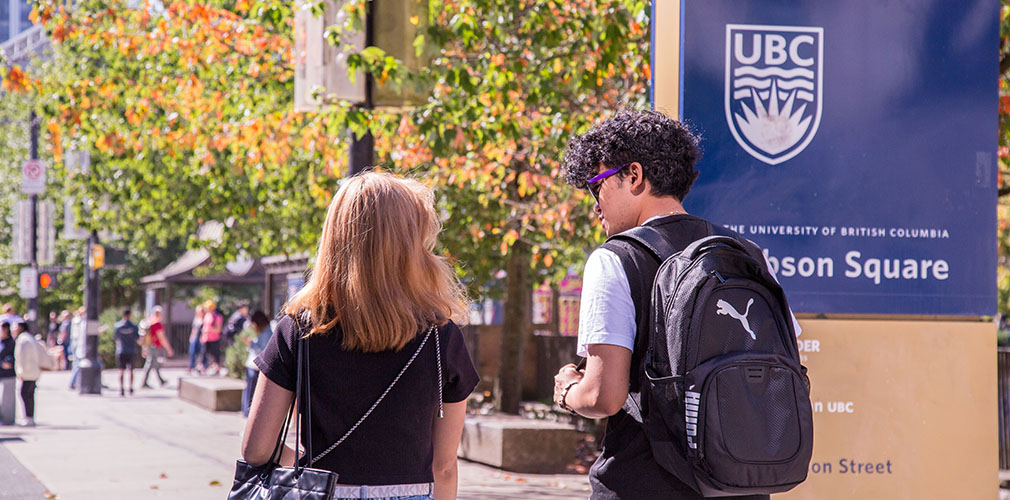 two students walking past a UBC sign