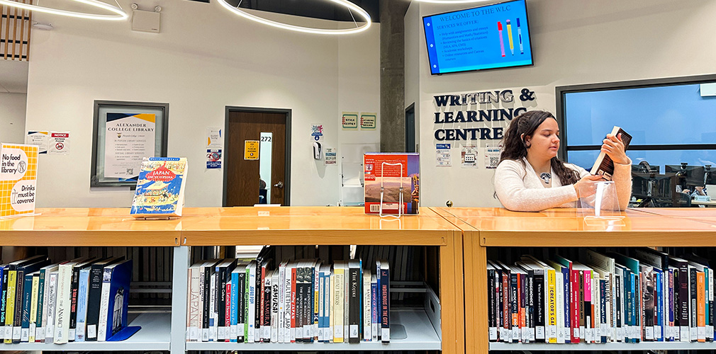 student looking at a book in the library