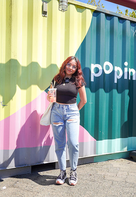 student posing in front of a colourful wall