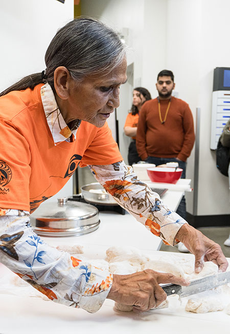 an elder teaching students how to make bannock