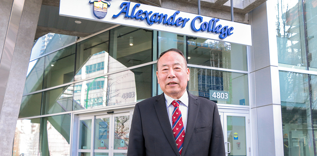 Our President, Gunagwei Ouyang, standing outside under the Alexander College sign